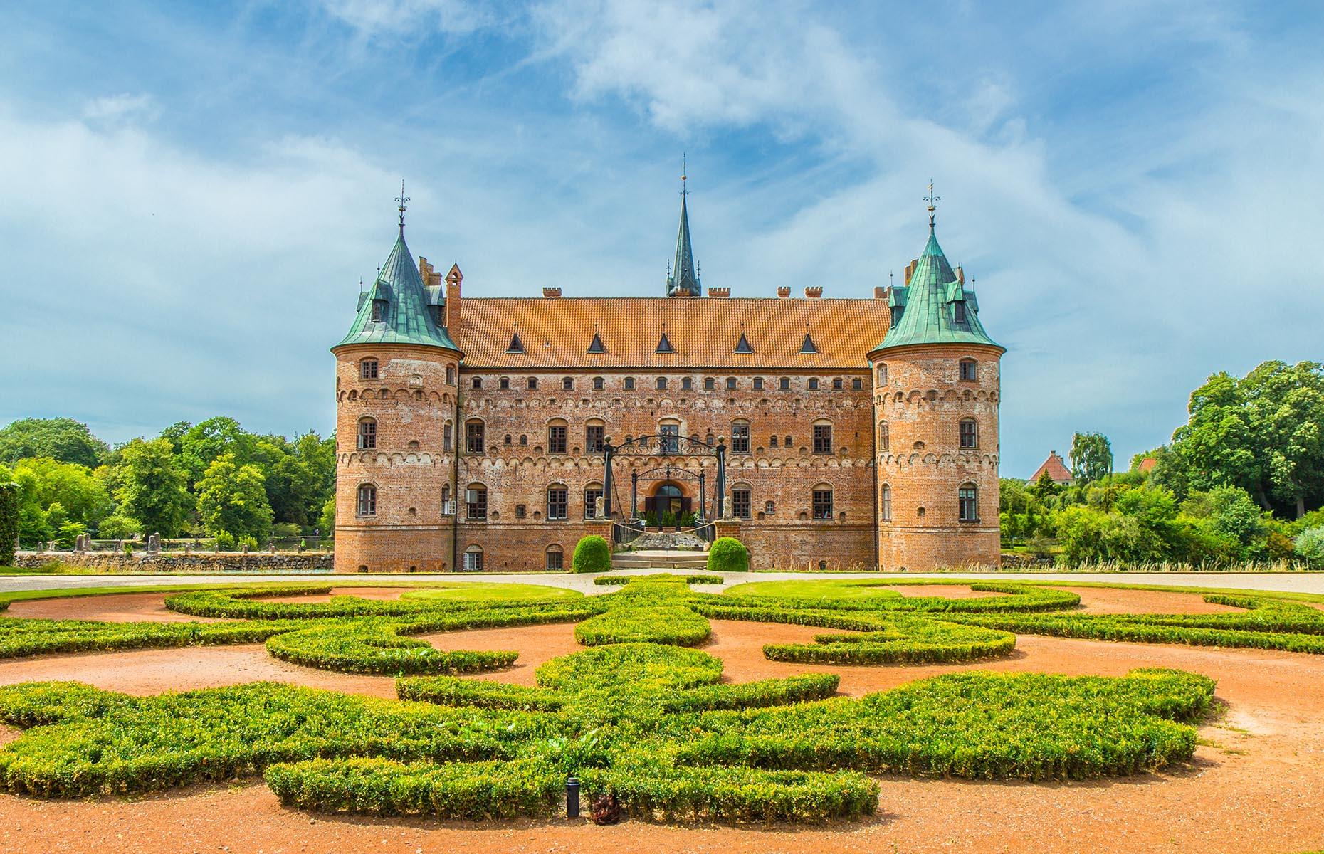 Slide 44 of 61: Built in the mid-16th century, Egeskov Castle, on the Danish island of Funen, is one of Europe’s finest Renaissance buildings, and was originally constructed for defense purposes. During the last 400 years, it has belonged to various families who have all lived in the striking structure. Today, it’s surrounded by an impressive garden and boasts the best-preserved moat in Europe.