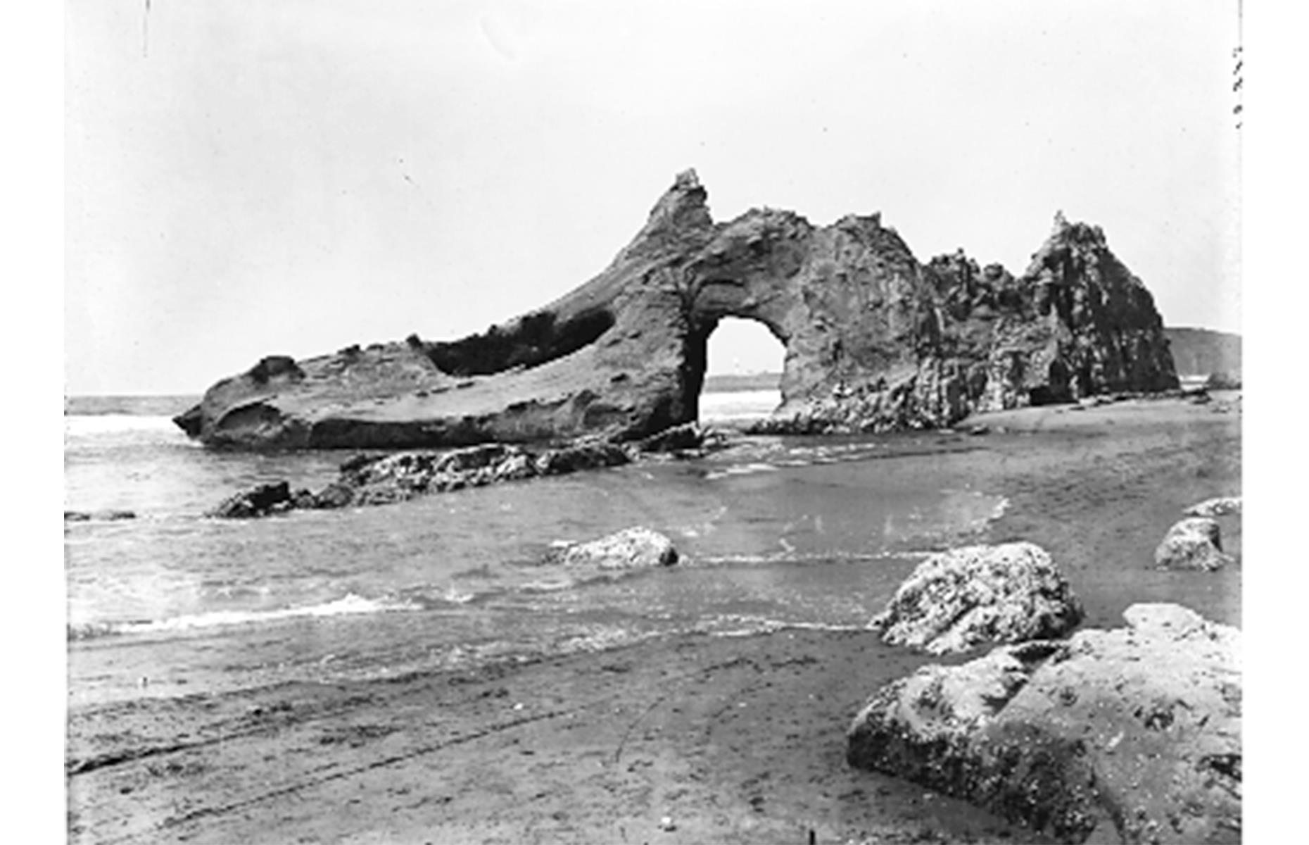 Slide 20 of 31: Jump-Off Joe is another natural Oregon landmark that didn’t stand the test of time. The arching sea stack rose just off the shore at Newport’s Nye Beach on Oregon’s Central Coast and was a popular attraction in the 19th century. It’s pictured here in 1910, a mere six years before it crumbled into the sea.