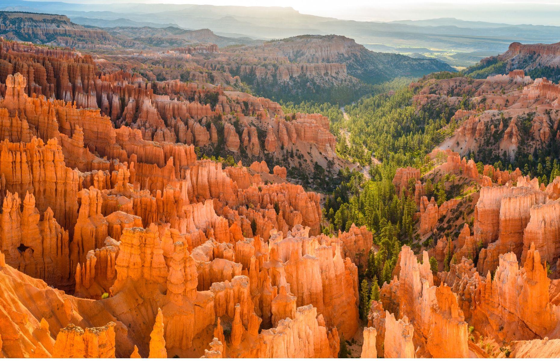 Slide 27 of 59: A demonstration of the power and beauty of nature, Bryce Canyon National Park is characterized by its crimson rock spires. Dynamic and distinctive, this canyon in Utah was formed by erosion over the course of about 15 million years. The hoodoos (the column-shaped rock formations) dazzle in shades of orange and red. Adventurous hikers can witness the surreal landscape for themselves by traversing the park's trails, ancient forests and natural amphitheaters.