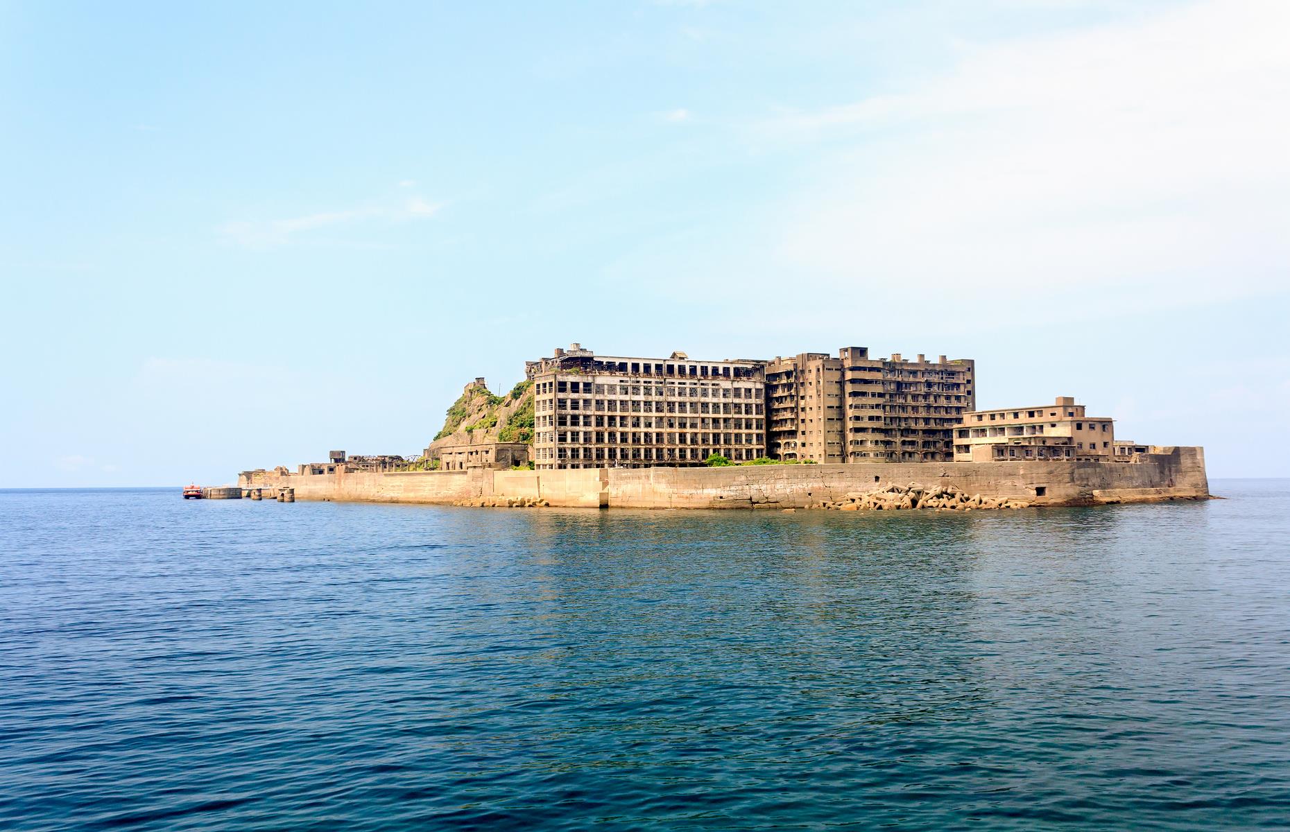 Slide 2 of 35: Hashima Island, also known as Battleship Island since its shape roughly resembles a ship, can be found off the coast of Nagasaki. Now a dilapidated collection of high-rises, the isle was once abuzz with people. Built up by the Mitsubishi Corporation, it had a huge part to play in Japan’s industrialization through the 1900s. There was a rich coal deposit beneath the island and an underwater coal mine thrived throughout the 20th century.