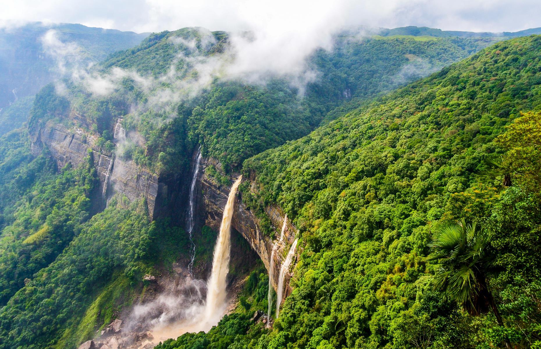 India’s tallest plunge waterfall has a dramatic drop of around 1,100 feet (335m) but it would be beautiful at a tenth of the height. It rushes over red-rock cliffs thickly blanketed with forest, which surrounds the falls with swathes of emerald green trees draped in mist. Heavy rainfall here in Meghalaya, in eastern India, keeps the landscape verdant, while locals have created bridges from living trees to help them get around in times of monsoon.