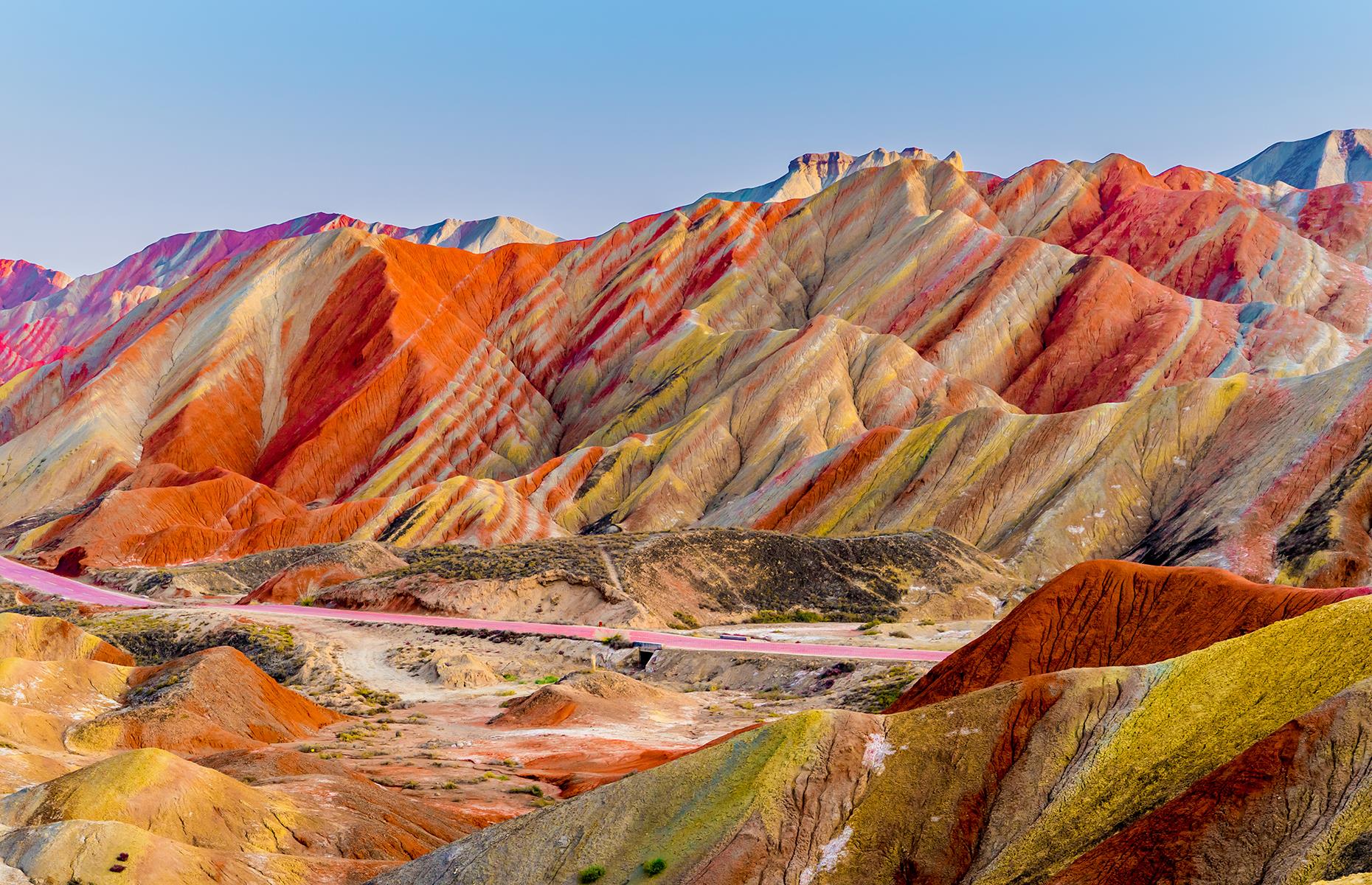 The stunning rainbow landscape of the Zhangye Danxia mountains, dubbed "the eye candy of Zhangye" by locals, is located in Gansu, China. Geologists believe the colorful layers of red sandstone and other mineral deposits built on top of each other over millions of years before a dramatic tectonic shift caused the mountains to form.