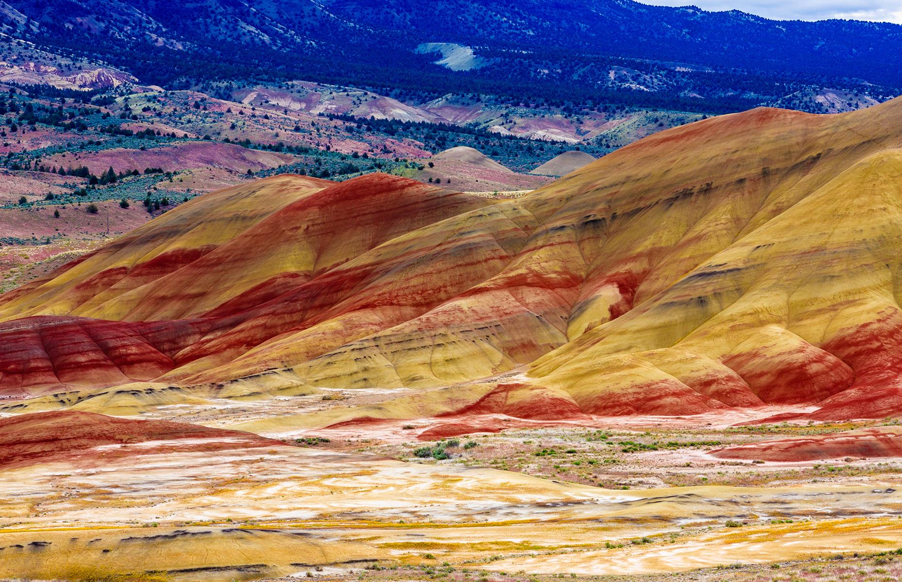 Slide 26 of 41: You'll have a hard time believing that these color-splashed mountains are real. With distinct lines of red, yellow, orange and black, these hills show how the climate and the geology has changed over time. Painted Hills Scenic Byway is the best way to explore them as the 161-mile (259km) route joins up the three archaeological sites of the John Day Fossil Beds National Monument, of which Painted Hills is one.