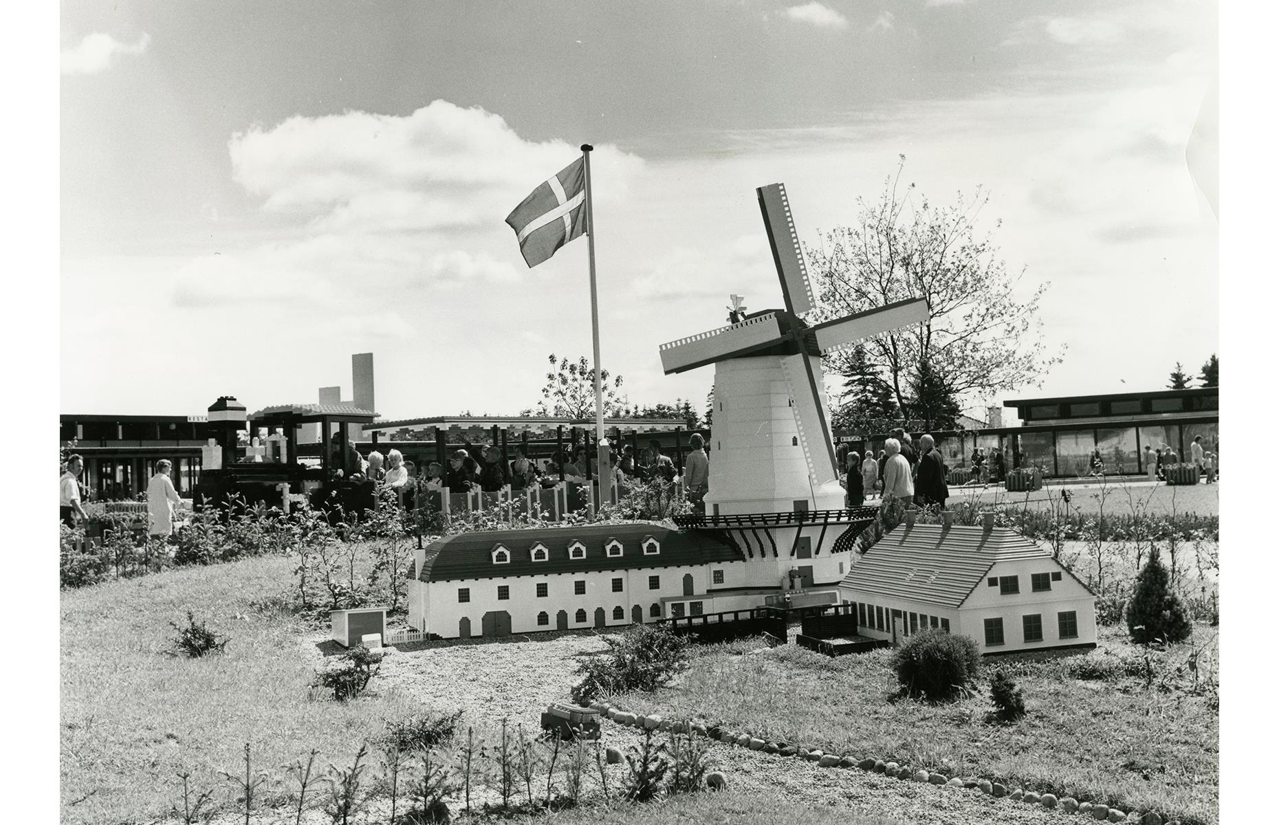 Slide 20 of 35: From the very beginning, Legoland’s intricate models made from rainbow blocks pleased visitors. In this picture from 1968, guests marvel at a Lego replica of Denmark's Dybbøl Mølle windmill as the Lego train rumbles along in the background.
