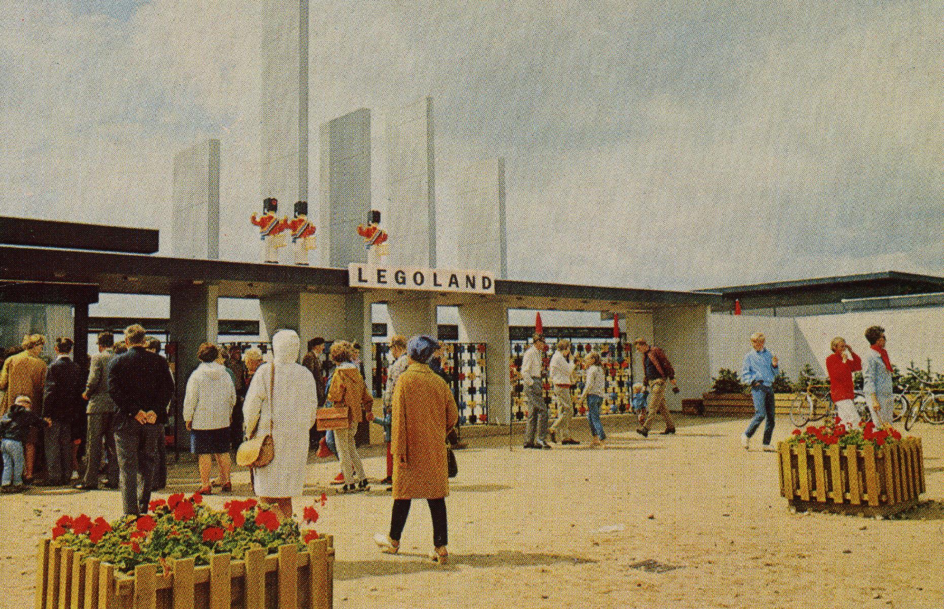 Slide 19 of 35: While Legoland parks are now dotted around the world, it all began in the town of Billund, Denmark. The original Legoland Park opened in 1968, and welcomes millions of visitors per year today. Crowds gather around the park’s vast entrance gates in this depiction from Legoland’s debut year.