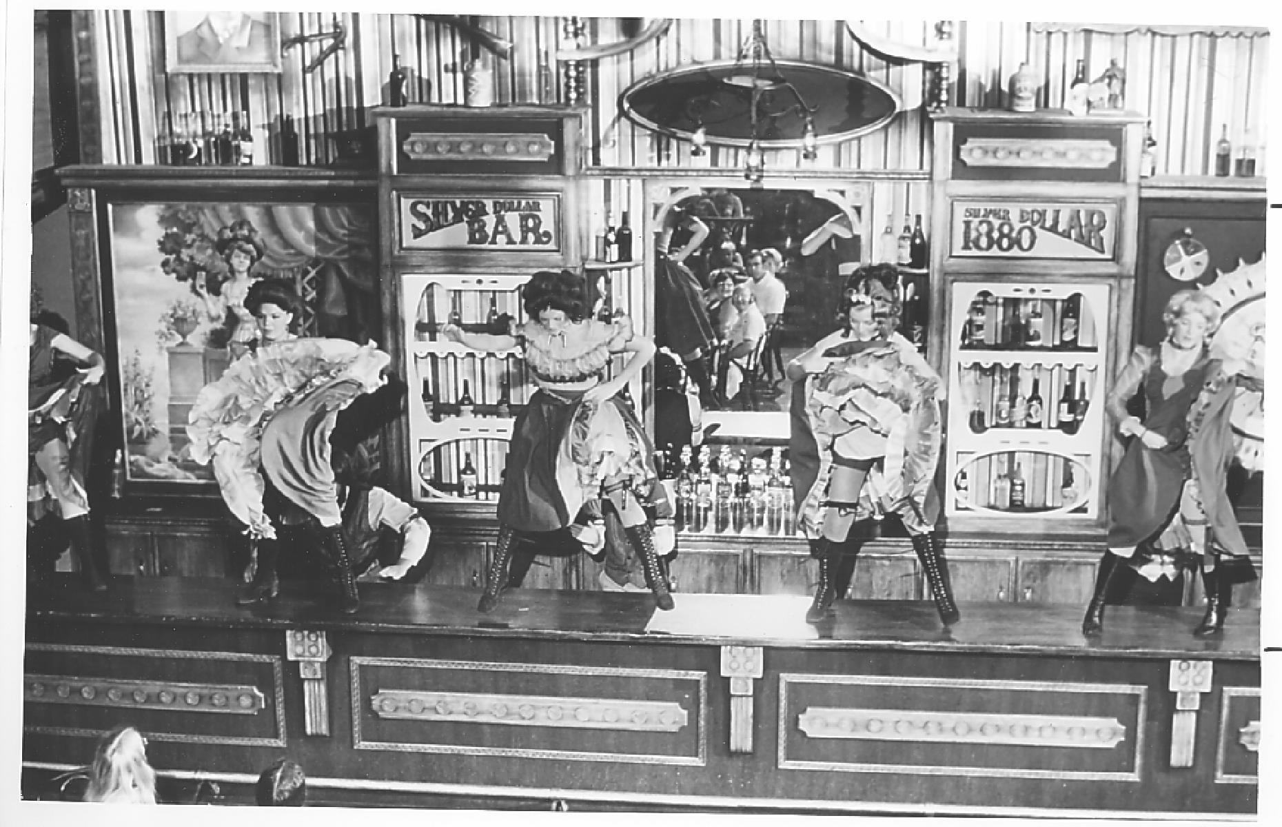 Slide 17 of 35: Alongside the carefully curated Old West-style attractions, visitors to the park could expect plenty of live entertainment. Pictured here is a stomping saloon show in the Silver Dollar Bar – look carefully and you can see the faces of delighted audience members in the mirror.