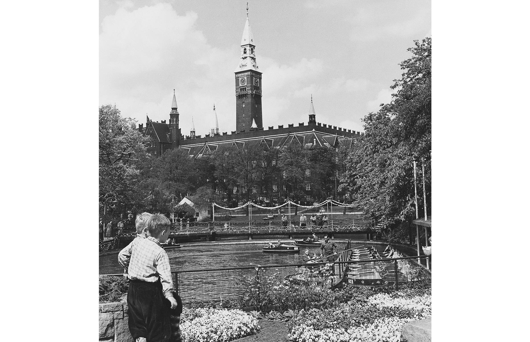 Slide 25 of 35: It's said that the Gardens were a favorite with Walt Disney, who paid a visit in the 1950s and even sought to emulate Tivoli's atmosphere in his own larger-than-life California park. The serene boating lake, pictured here in the late 1950s, remains the park's showpiece, despite the addition of mammoth thrill rides and attractions. Here you can spot Copenhagen's City Hall in the background too.