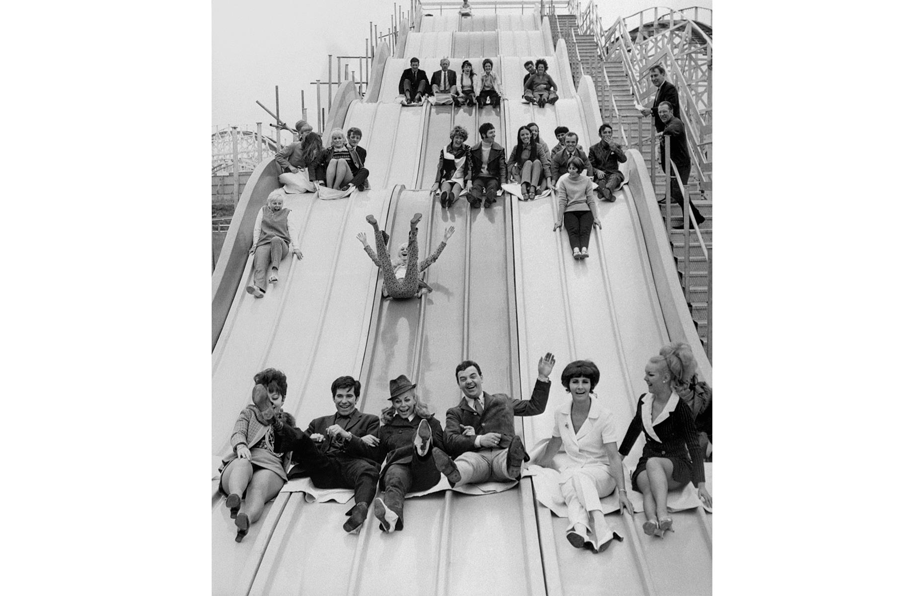 Slide 6 of 35: There was – and is – plenty more beyond the roller coasters and thrill rides at Blackpool Pleasure Beach, though. Here, in the late 1960s, a fun-seeking bunch slip down the park's mammoth nine-lane slide. Next stop? To a confectionery stand to pick up a stick of Blackpool's famous rainbow rock.