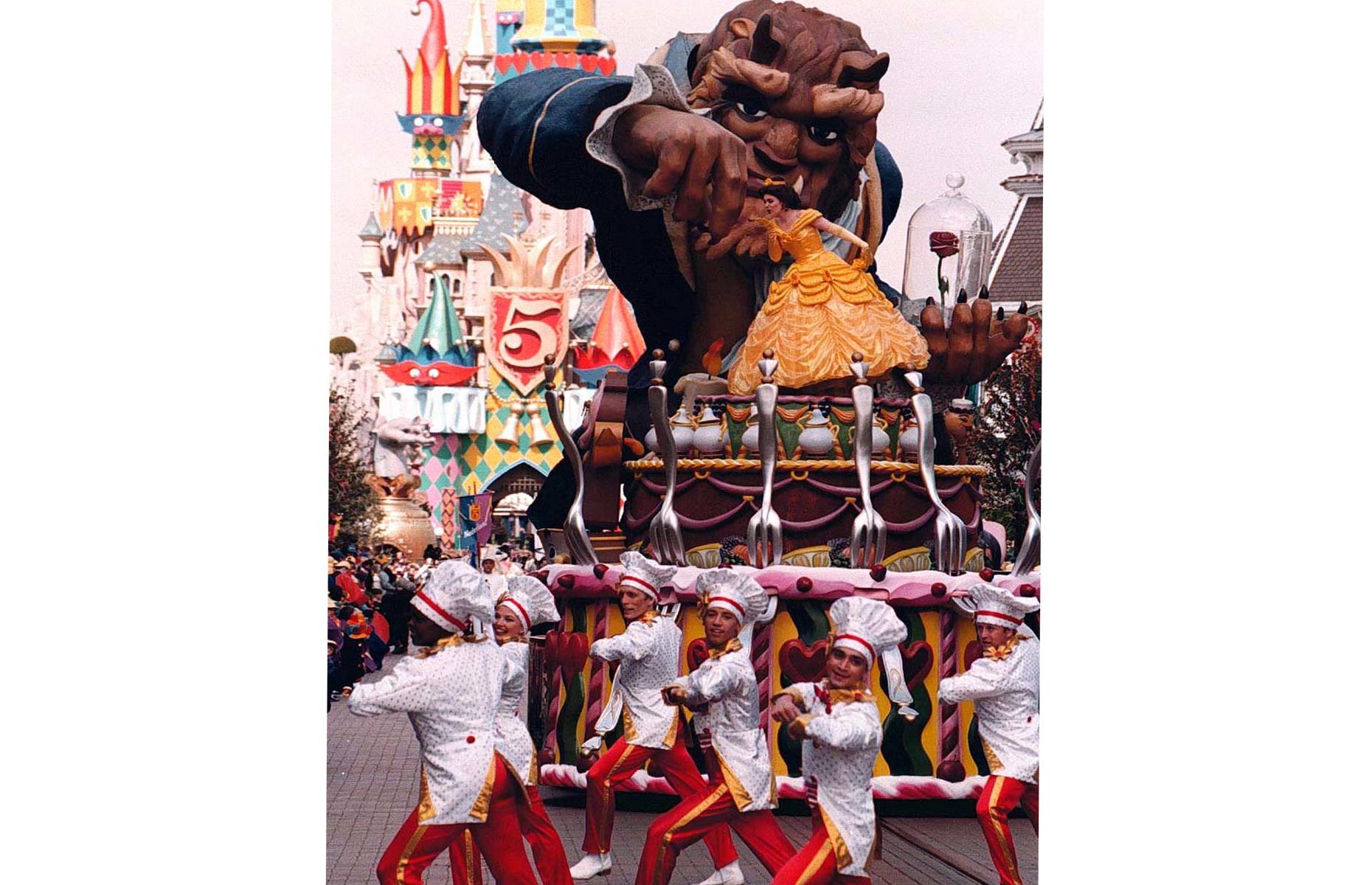 <p>One of Disneyland Paris's most striking 5th anniversary floats was the one carrying a mammoth Beast (from <em>Beauty and the Beast</em>) and Belle in her famous yellow dress. In the background of this photo, you can make out the Sleeping Beauty Castle, which was given a new look for the 5th anniversary celebrations. The so-called Château du Fou was bedecked with jester hats and golden bells, in part to celebrate the release of <em>The Hunchback of Notre Dame</em> film the previous year.</p>