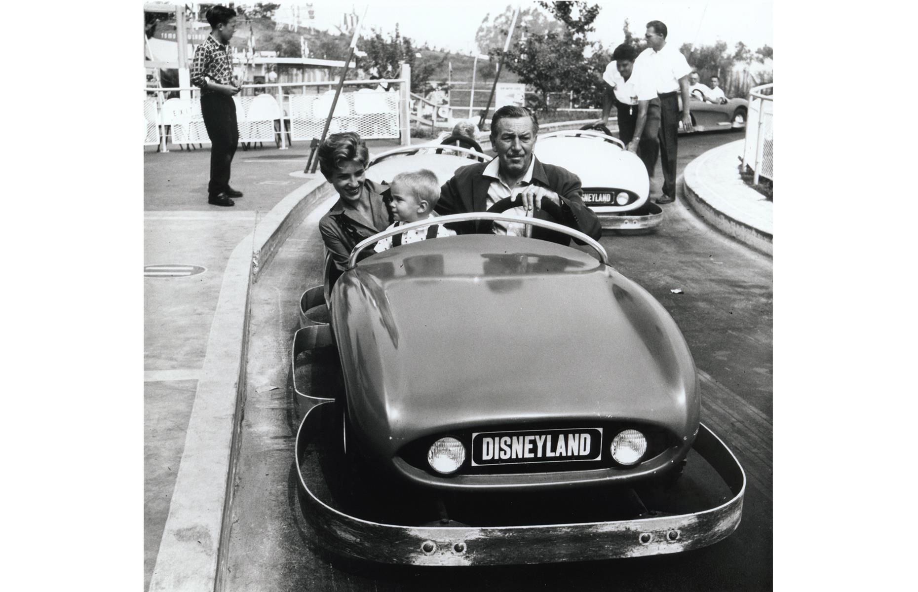Slide 13 of 38: Another vintage Disney family snap, this one shows the park creator with his grandson and his daughter too. They're whizzing around on Autopia, a miniature speedway that still exists today. It was one of the park's opening attractions, debuting in futuristic Tomorrowland, where it remains.