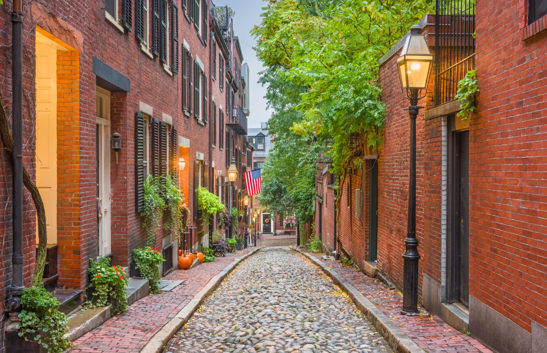Slide 58 of 100: Acorn Street, in Boston's charming Beacon Hill neighborhood, is often tipped as the most photographed street in the country – and it's not hard to see why. The snug cobblestoned lane is lined with gas lamps and red-brick row-houses draped with the American flag, their window boxes spilling with greenery. It swelled with tradespeople and makers in the 1800s and today the homes are worth millions of dollars.