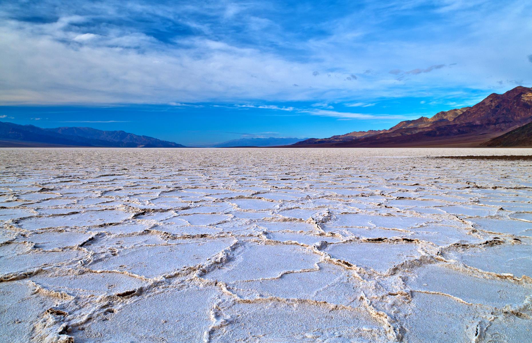 Slide 29 of 100: The lunar expanse of Death Valley's Badwater Basin represents the lowest point on the North American continent. An enormous area of salt flats, it sinks to some 282 feet (86m) below sea level, an intricate tapestry of interlocking polygons. It's also periodically flooded, leaving a mirror-like sheet of water across its flat surface for a short time. Find more of America's most stunning natural wonders here.