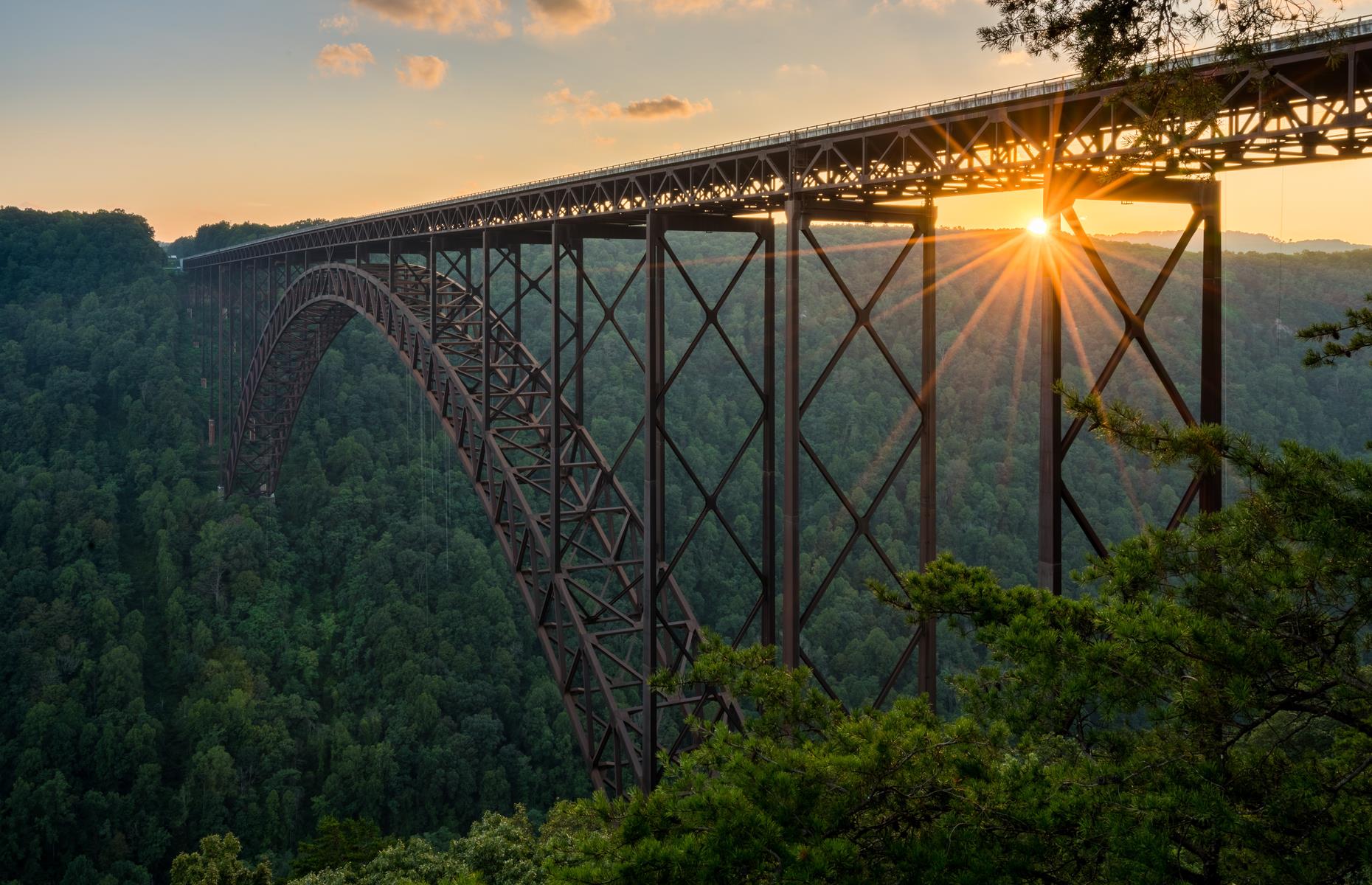 Slide 95 of 100: This enormous steel-arch bridge has spanned West Virginia’s New River Gorge since the 1970s. It's among the longest bridges of its kind in the world, and its height is dizzying: it soars about 876 feet (267m) above the waters below. The mammoth feat of engineering sits in stark contrast to the lush scenery all around. Now take a look at more impressive bridges in the USA.