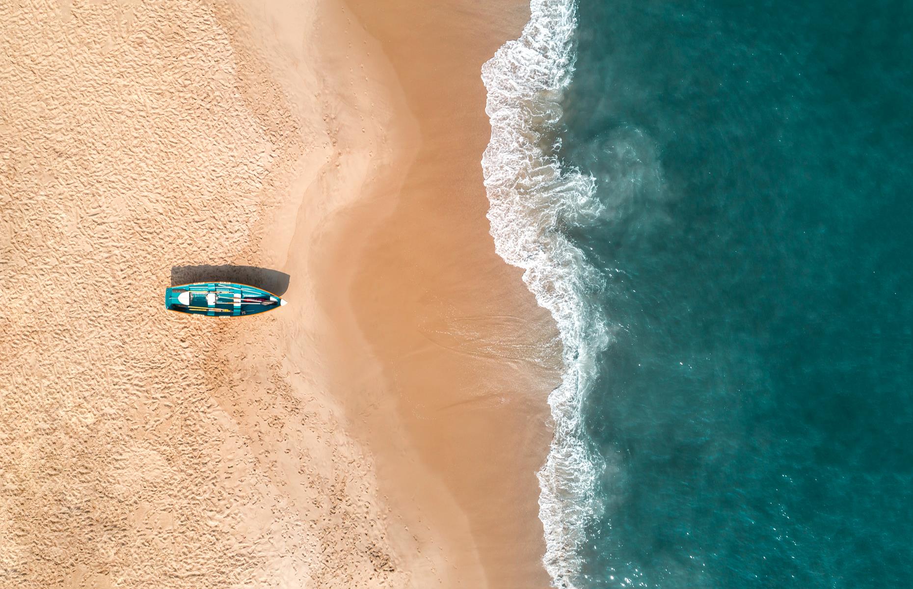 Slide 16 of 45: Given the golden sand and teal waters, you'd be forgiven for thinking that this shot was taken over the Caribbean. But it was actually captured in New Jersey's Cape May, a seaside resort known for its fine beaches and quaint historic district. Here a wooden boat seen from above sits on Cape May's peach-colored shore which is lapped by a frothing Atlantic Ocean.