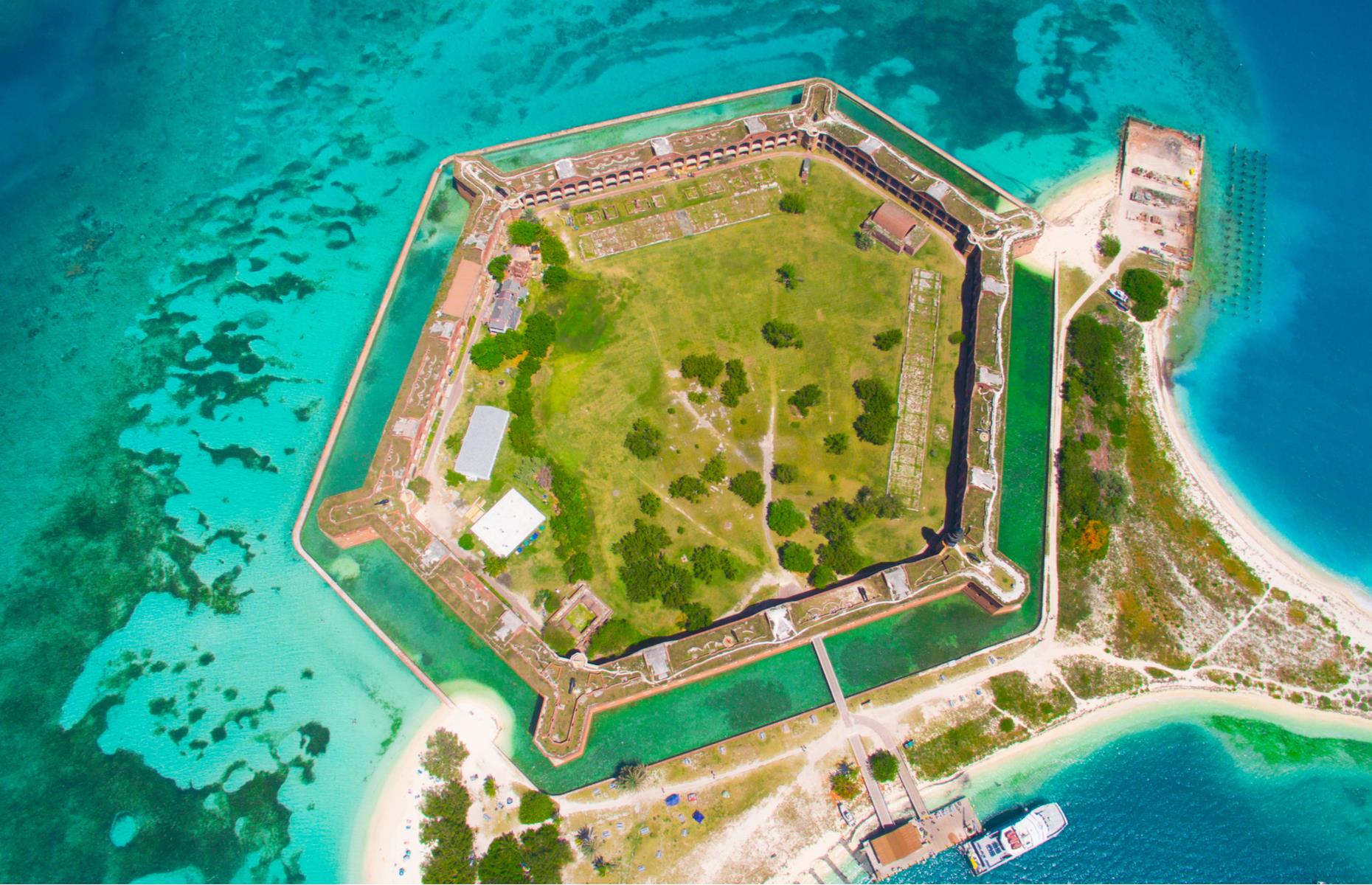 Slide 35 of 45: Hexagonal Fort Jefferson in Dry Tortugas National Park looks pretty dramatic from above, as the fort's lumbering gray walls contrast with the coral-filled waters all around. Dating to the 19th century, the fort is situated on Garden Key and can be reached via ferry or seaplane. 