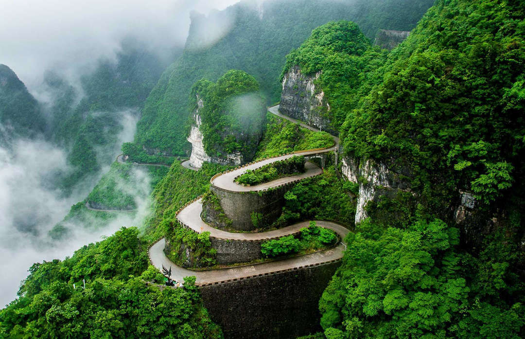 Slide 31 of 44: This spectacularly steep and winding road can be found in the Tianmen Mountain National Park in China's Hunan Province. It curls up the mountain for seven miles (11km) with 99 nerve-wracking bends and precipitous drops. The road ends at a natural gap near the mountain's peak. Although, you'll need to walk 999 steps after you've parked to reach the sacred crevice, which is known as Heaven's Door.