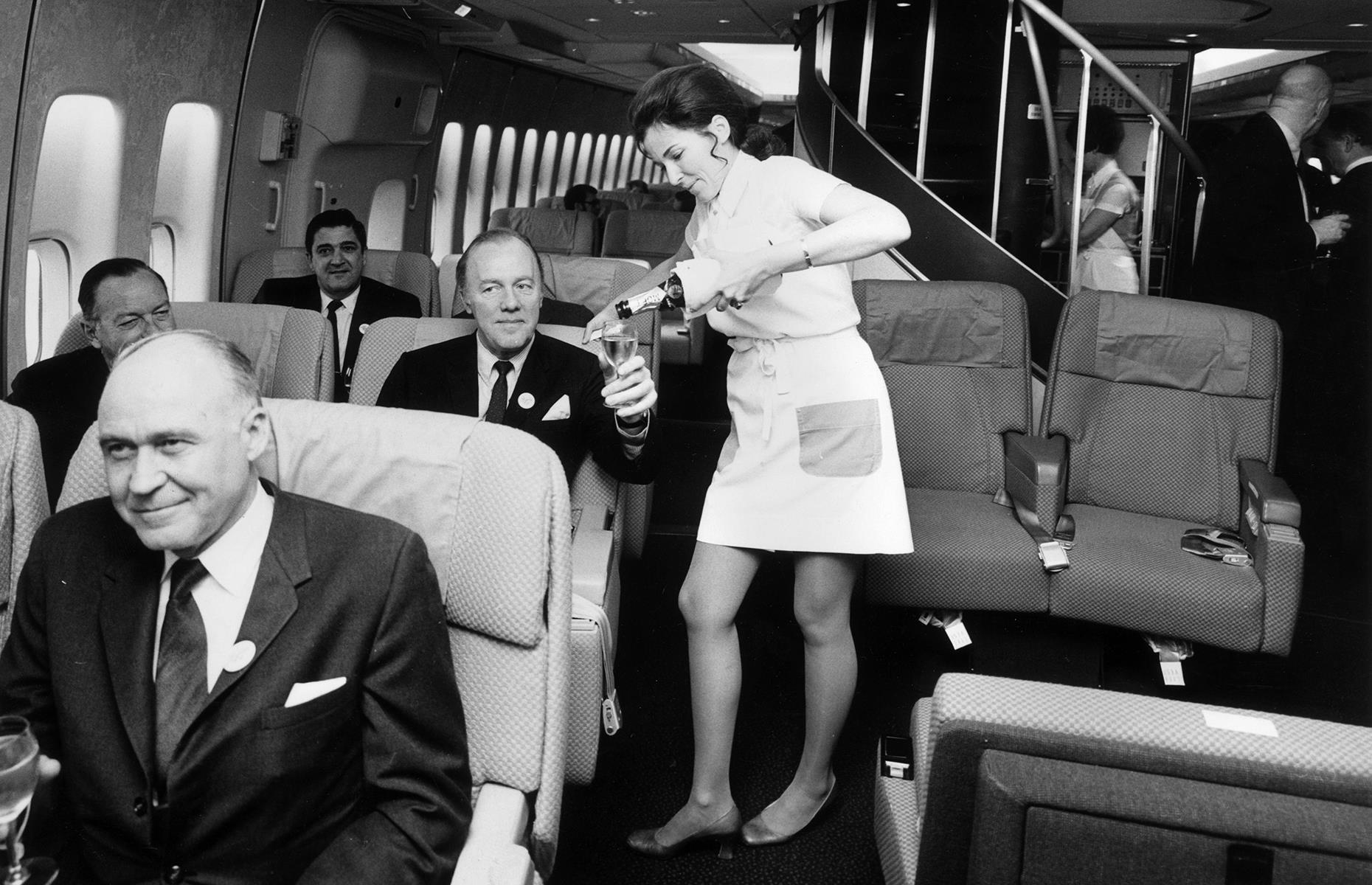 Those passengers who could afford it needn't skimp on luxury, though. Here, travelers in first class are served Champagne by a flight attendant on a Boeing 747 operated by Pan Am in 1970.