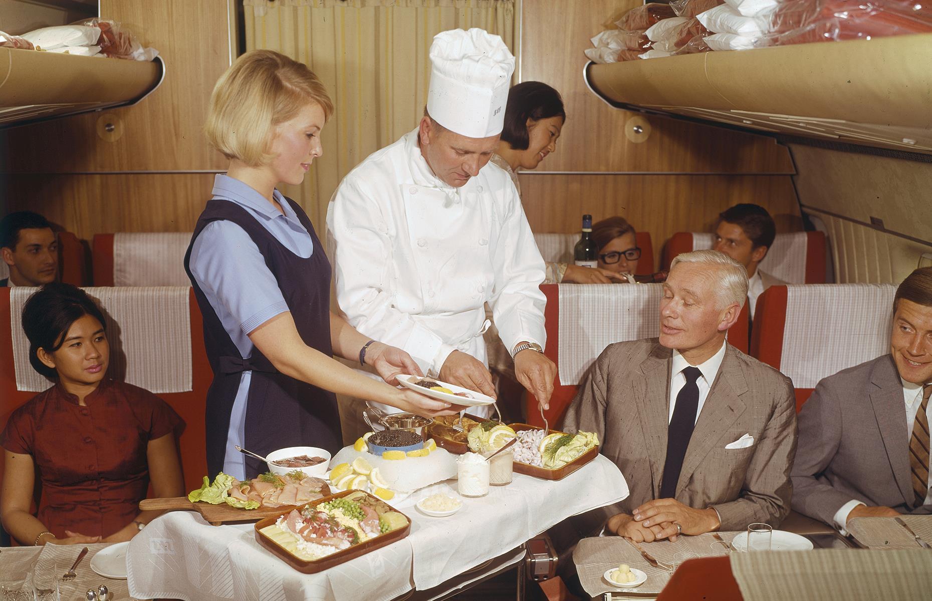 Passengers are receiving similar treatment on this SAS (Scandinavian Airlines) flight in 1969. In this instance, the chef has even come to serve and greet dining first-class passengers. Flying was such an important occasion that it was common for passengers to come aboard in their finest clothes too, with women in dresses and men opting for tailored suits.