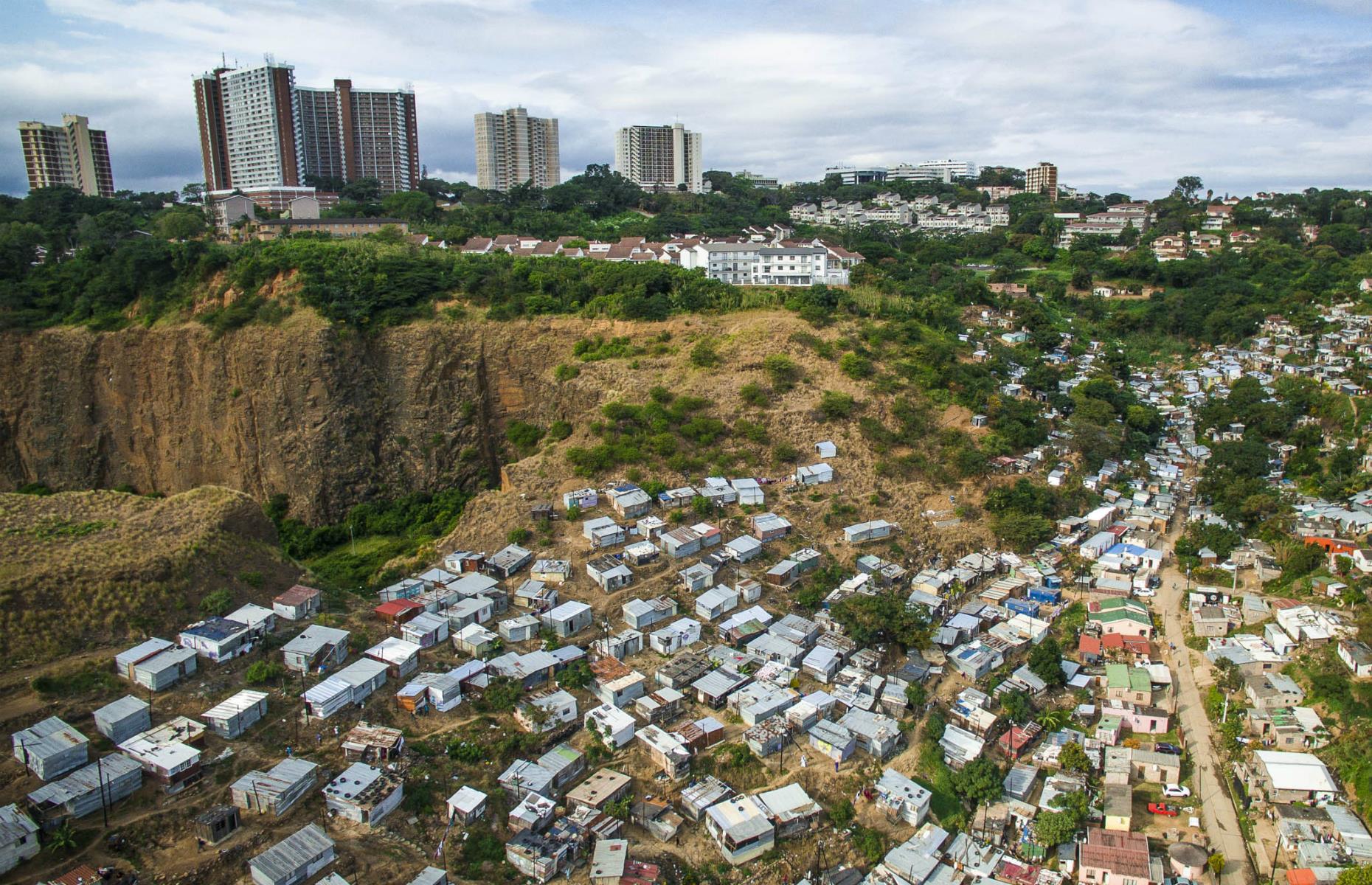 <p>This image shows the road that leads down from Morningside to the Umgeni River, which is lined by shacks. These slums are at risk from poor drainage and torrential rain, as well as the threat of fire, while richer inhabitants sit higher up on the hill, avoiding these concerns.</p>