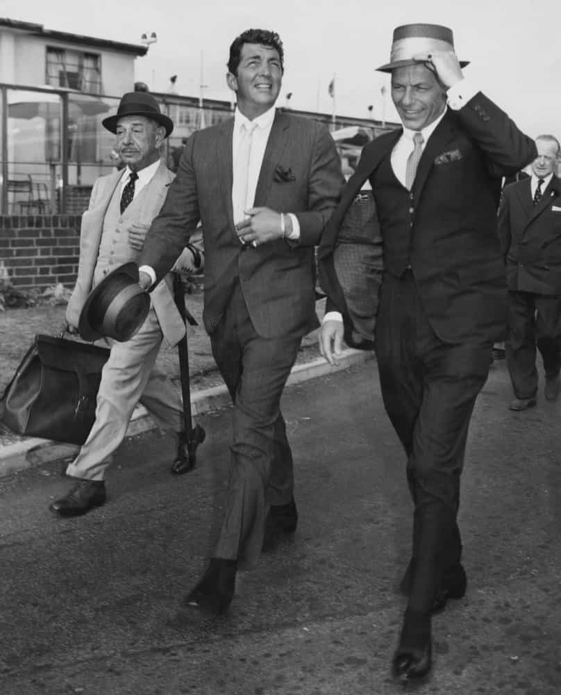 Dean Martin und Frank Sinatra landen am Londoner Flughafen, begleitet von ihrem Freund, dem berühmten Beverly Hills-Gastronom Mike Romanoff.