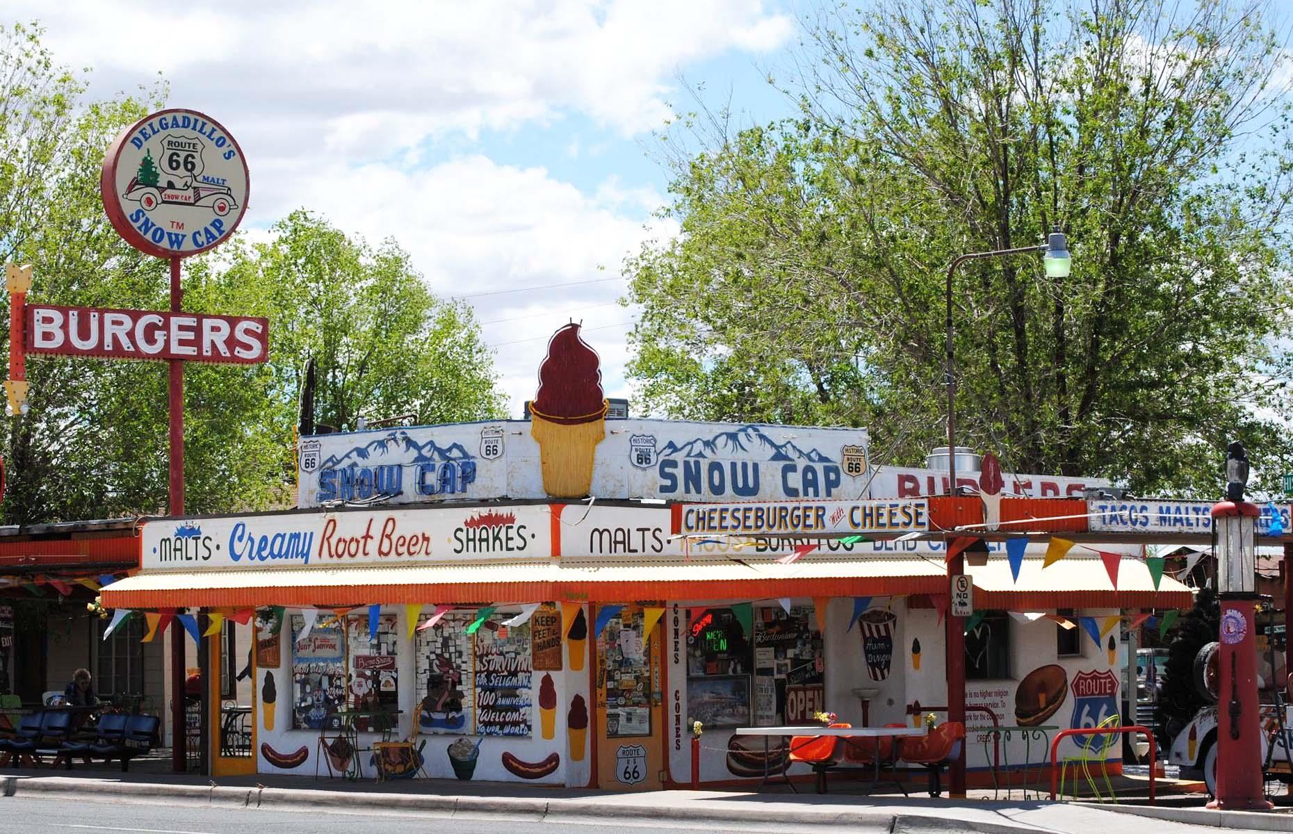 <p>This historic roadside stop on the former Route 66 in Seligman is a must-visit. It dates back <a href="http://john-delgadillo.squarespace.com/">to the 1950s</a>, is constructed from scrap wood and out the front is a 1936 Chevrolet hardtop decorated with <a href="https://thedyrt.com/magazine/lifestyle/guide-to-rv-road-tripping-along-route-66/">a Christmas tree</a>. Food-wise, the green chili burger, fries and a shake is <a href="https://www.yelp.com/biz/delgadillos-snow-cap-drive-in-seligman?q=green">what to order.</a> It has closed now for the season, but will reopen <a href="https://www.facebook.com/Delgadillos-Snow-Cap-419894931438847/?ref=page_internal">next spring.</a></p>
