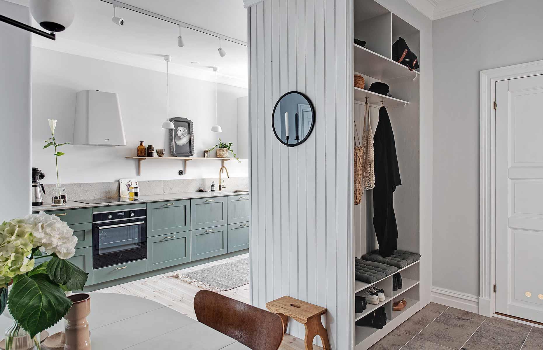 <p>Don’t be afraid of squeezing more functional zones into your open-concept layout. This <a href="https://www.loveproperty.com/gallerylist/97075/smart-room-dividers-that-break-new-boundaries">compact room divider</a> has been fitted with coat hooks and shoe cubbies, as well as higher shelves for bags and accessories. Not only does it add valuable storage space, but it helps define the transition between the kitchen and dining area in this snug multipurpose room too.</p>