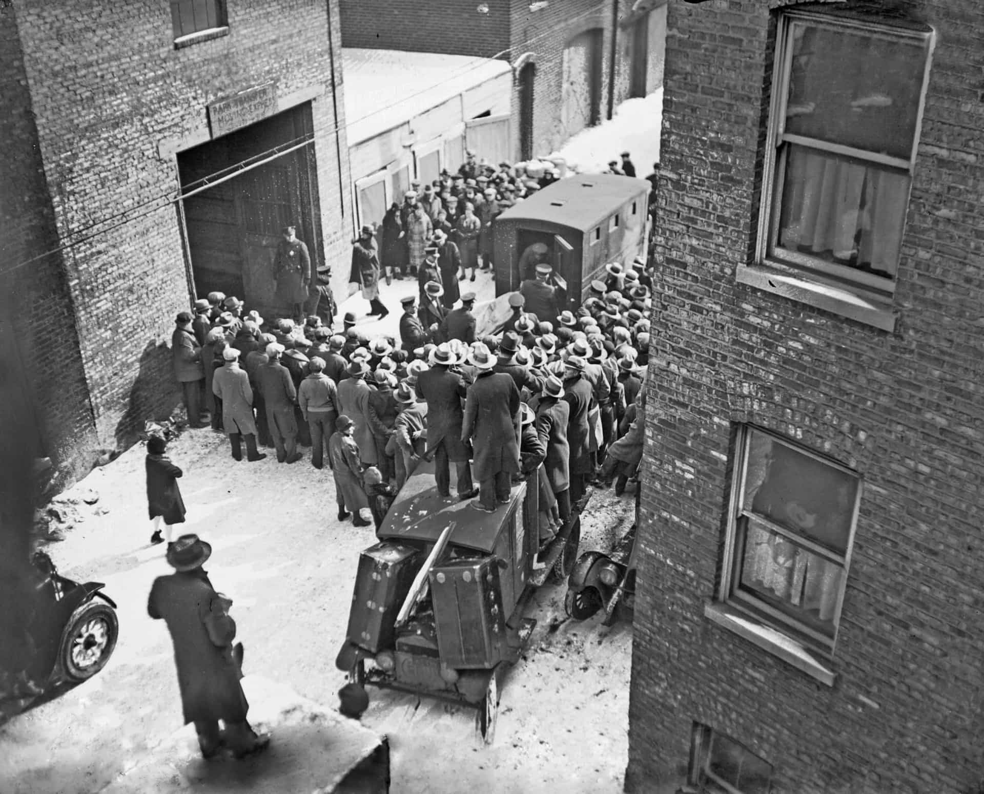 <p>On February 14, 1929, seven members and associates of Moran's North Side Gang were gunned down by four unknown assailants who were dressed as police officers. The killings took place inside a garage in the Lincoln Park neighborhood of Chicago. Capone was widely assumed to be behind the killings. Pictured is a crowd of onlookers gathered outside the premises as one of the murder victims is placed in an ambulance.</p>
