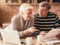 a man and a woman sitting at a table with a cup of coffee: 10 Small Changes To Stay On Track With Your Retirement Goals