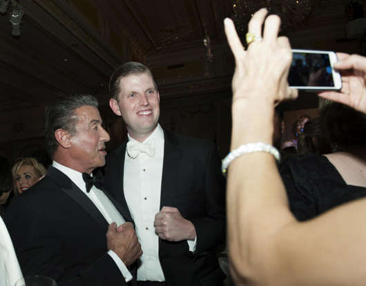 Eric Trump et al. standing next to a man in a suit and tie