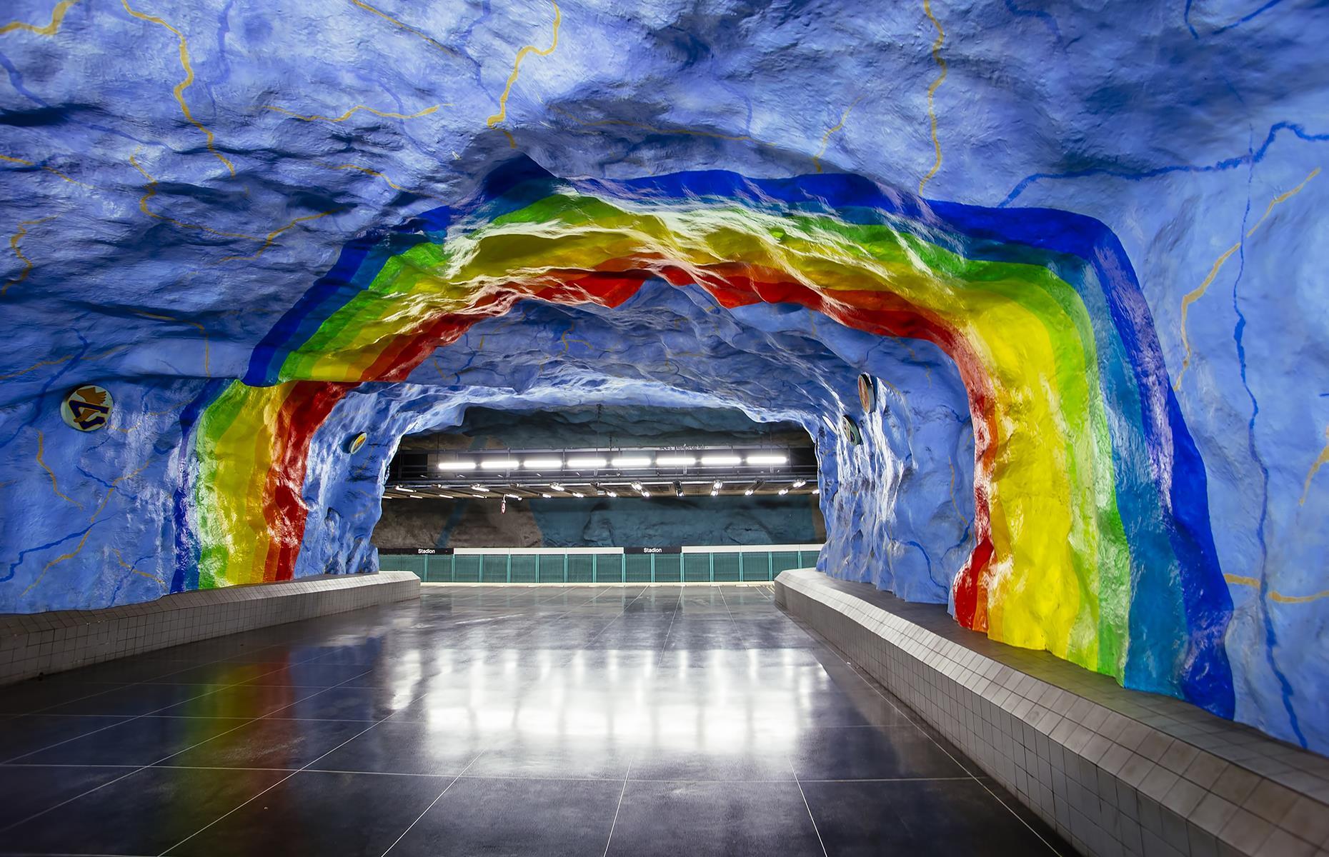 Painted sky-blue with rainbow patterns all over, including a massive rainbow arch stretching across the tunnel connecting two platforms, Stadion station was decorated to commemorate the 1912 Stockholm Olympics. The rainbow represents the colors in the Olympic rings.