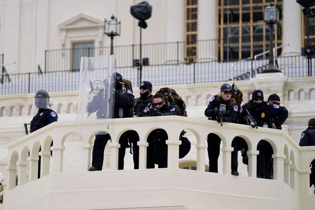 Slide 5 of 12: Police keep a watch on demonstrators who tried to break through a police barrier, Wednesday, Jan. 6, 2021, at the Capitol in Washington. As Congress prepares to affirm President-elect Joe Biden's victory, thousands of people have gathered to show their support for President Donald Trump and his claims of election fraud.