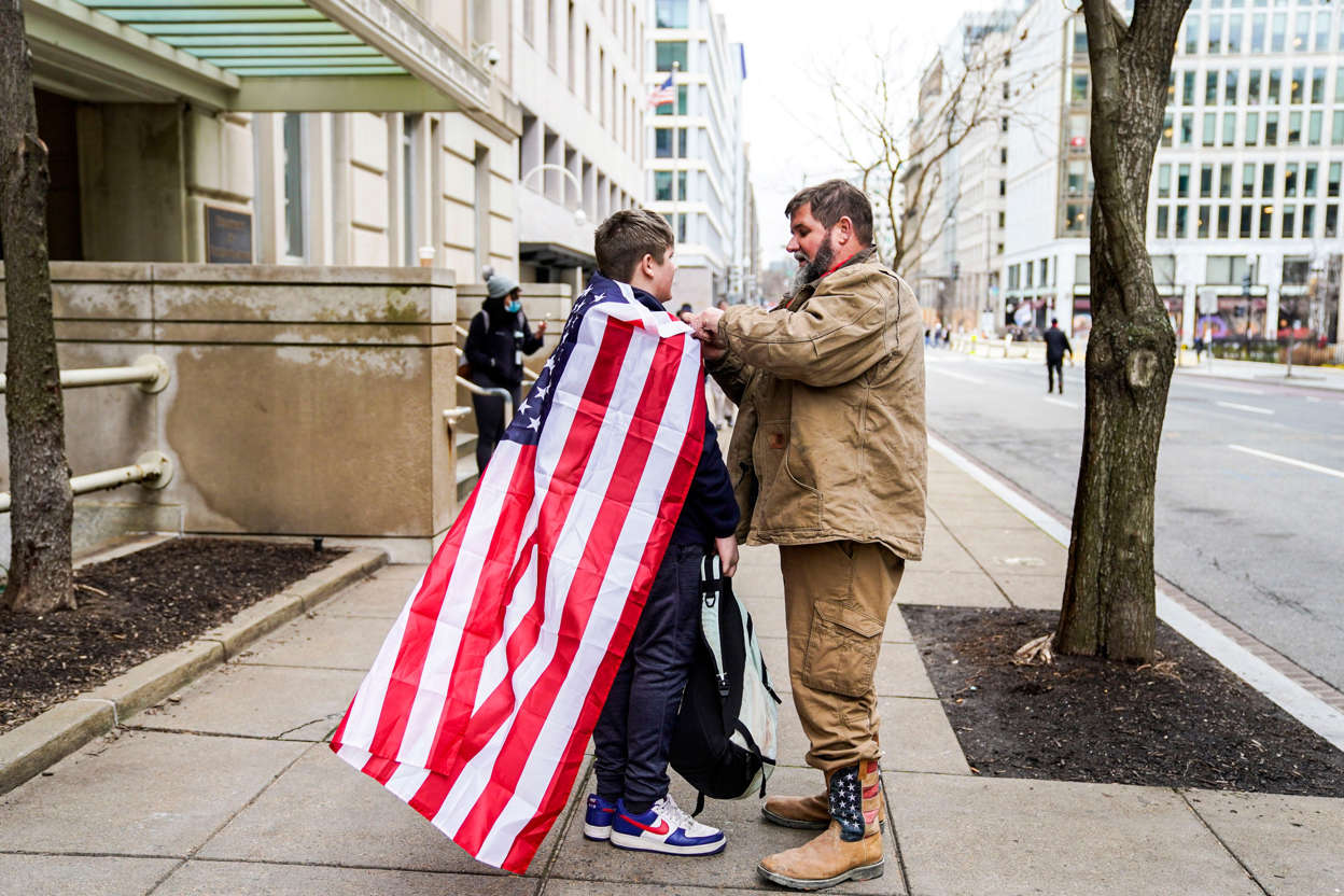 Slide 53 of 76: Blake Rizzo, 13, stands still while his father, Paul Rizzo, ties the American flag around his neck during protests in Washington, DC as the U.S. Congress meets to formally ratify Joe Biden as the winner of the 2020 Presidential election on Jan. 6, 2021.