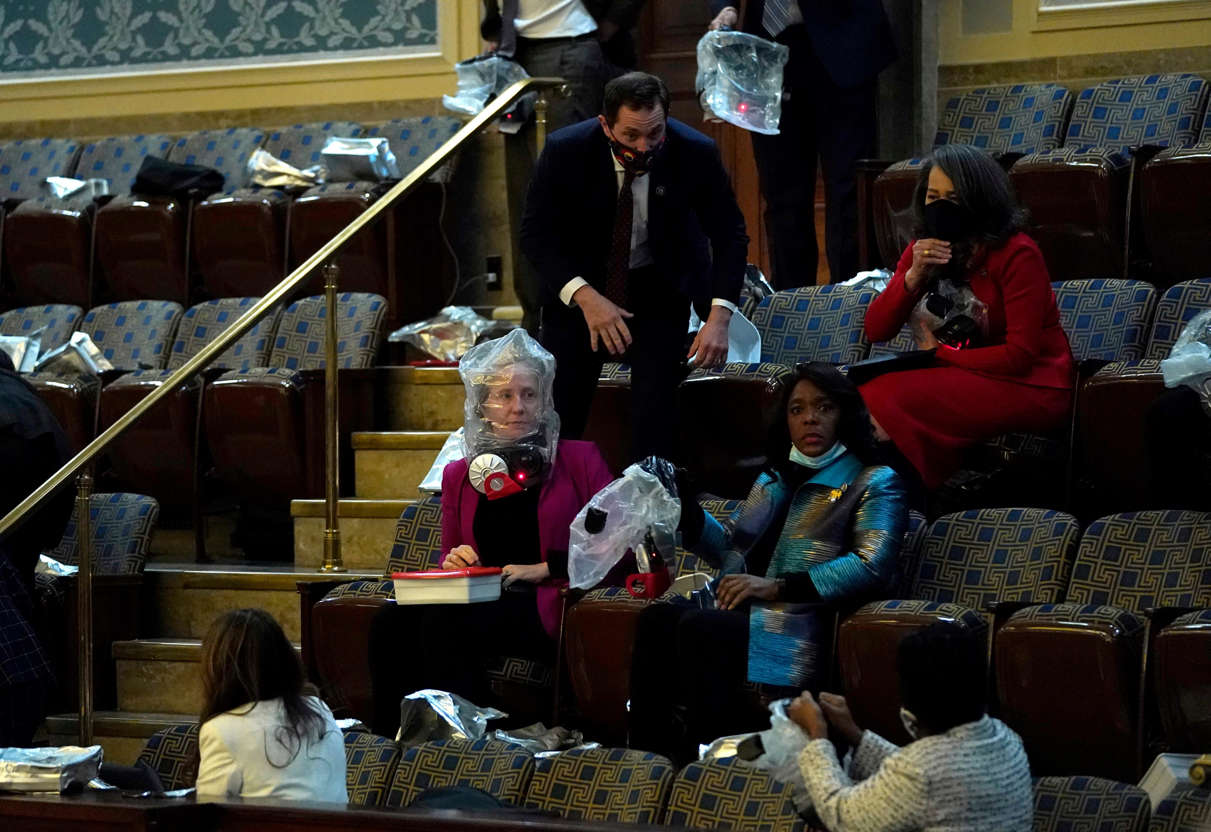 Slide 29 of 76: People wear protective gear as protesters attempt to enter the House Chamber during a joint session of Congress on January 06, 2021 in Washington, DC.
