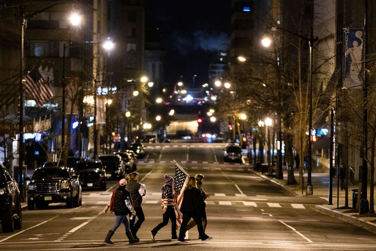 Slide 75 of 76: A group with an American flag cross a quiet 12th Street in the direction of pro-Trump rallys on Jan. 6, 2021 in Washington, DC.