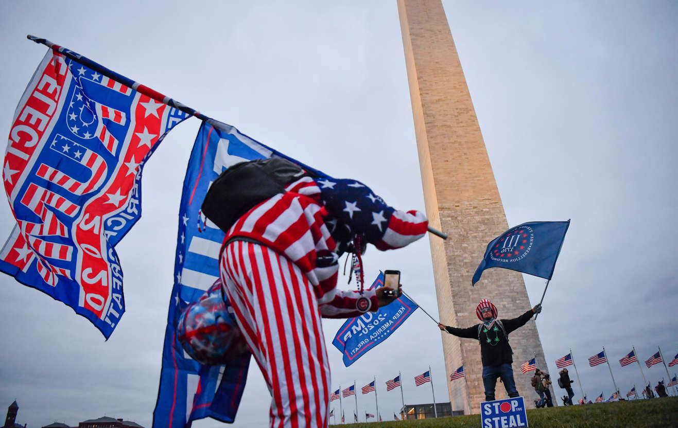 Slide 62 of 76: Trump supporters take photos near the Washington Monument before the start of a rally near the White House in Washington, DC on Jan. 6, 2021.