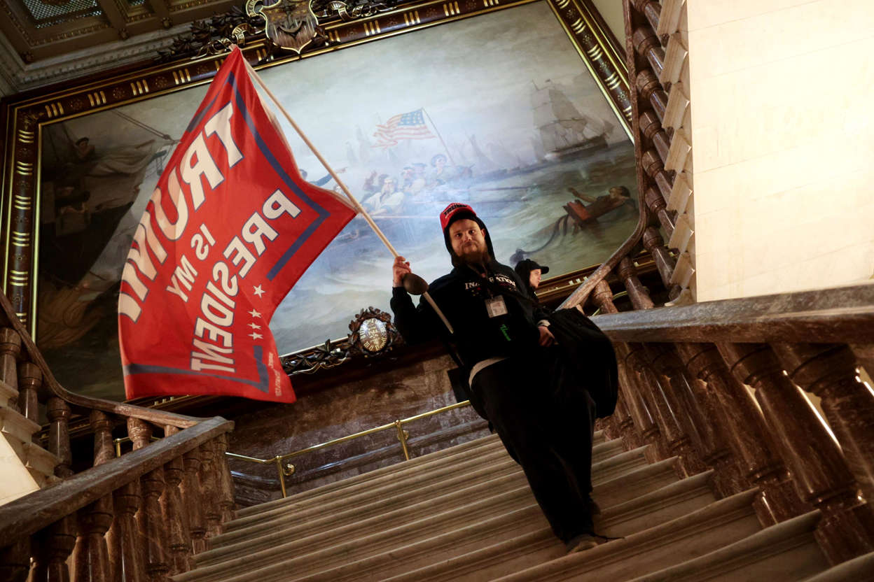 Slide 35 of 76: A protester holds a Trump flag inside the US Capitol Building near the Senate Chamber on January 6, 2021 in Washington, DC.