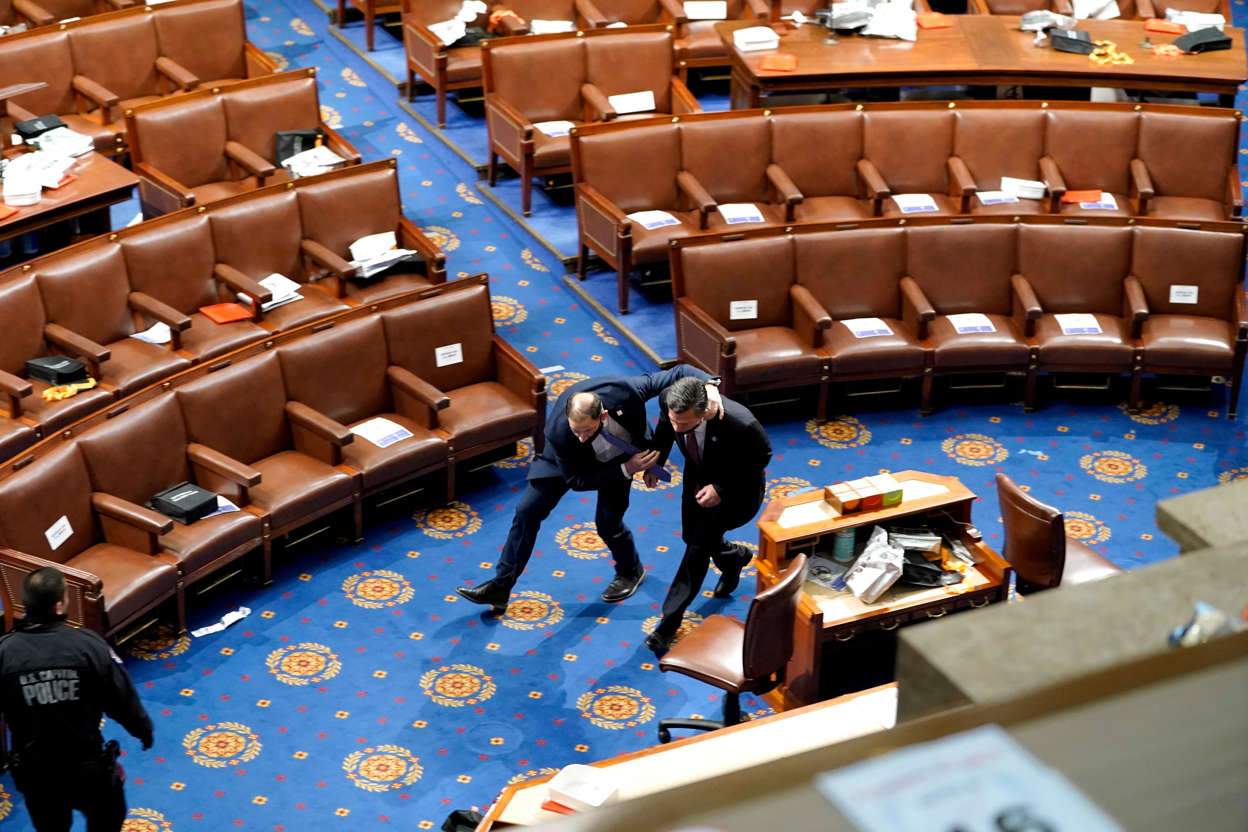 Slide 25 of 76: Members of congress run for cover as protesters try to enter the House Chamber during a joint session of Congress on January 06, 2021 in Washington, DC.