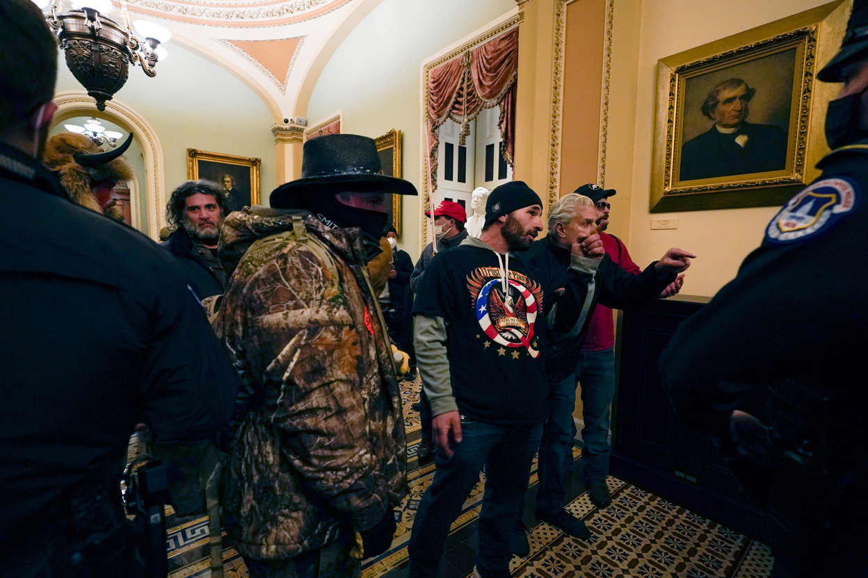 Slide 34 of 76: Doug Jensen (C), 41, of Des Moines and other Pro-Trump rioters confront U.S. Capitol Police officers in a hallway near the Senate chamber at the Capitol in Washington, Wednesday, Jan. 6, 2021. Jensen was arrested by the FBI at 1 a.m. on Saturday, Jan. 9, 2021.