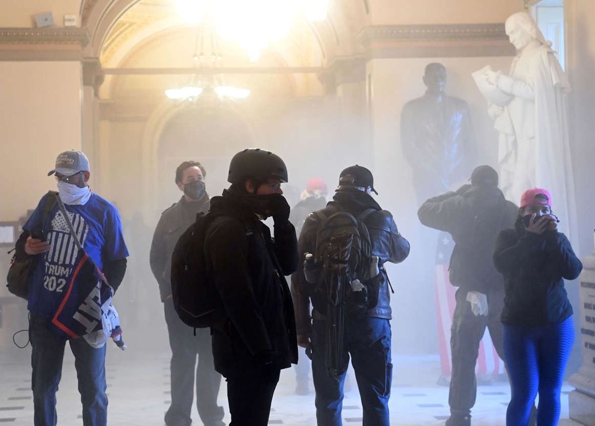 Slide 28 of 76: Supporters of US President Donald Trump enter the US Capitol as tear gas fills the corridor on January 6, 2021, in Washington, DC.