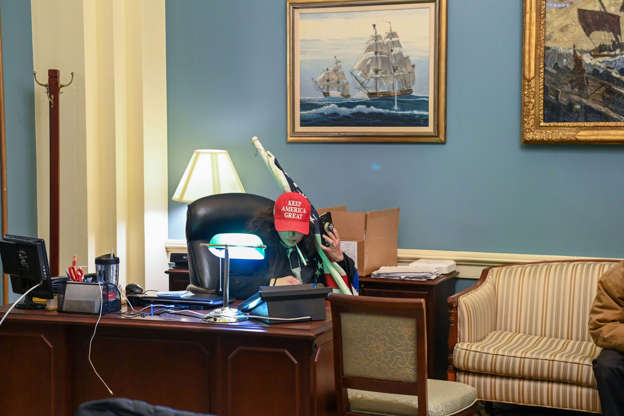 Slide 12 of 12: A supporter of US President Donald Trump sits at a desk after invading the Capitol Building on January 6, 2021, in Washington, DC.