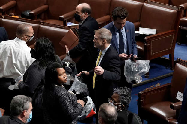 Slide 4 of 12: House of Representatives members leave the floor of the House chamber as protesters try to break into the chamber at the U.S. Capitol on Wednesday, Jan. 6, 2021, in Washington. Rep. Jim Jordan, R-Ohio, is at center.