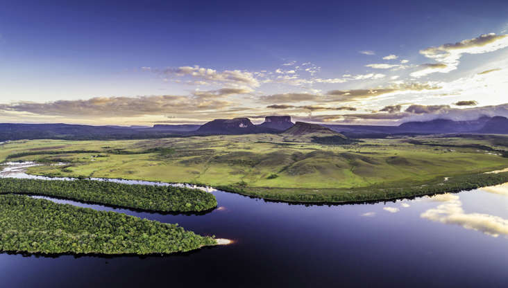 Слайд 2 из 34: Aerial  morning panoramic view of Canaima National Park tepuis and the Carrao river at Ucaima. At the background Kurun, Kusary and Kurawaik Tepuis. Canaima is a world known place for the beauty of nature and countless waterfalls. Canaima is visited for tourist all around the world during all year round. During rainy season navigation on the Churun river is possible to visit the Angel falls, the tallest waterfall in the world with 976 mt of water free fall.