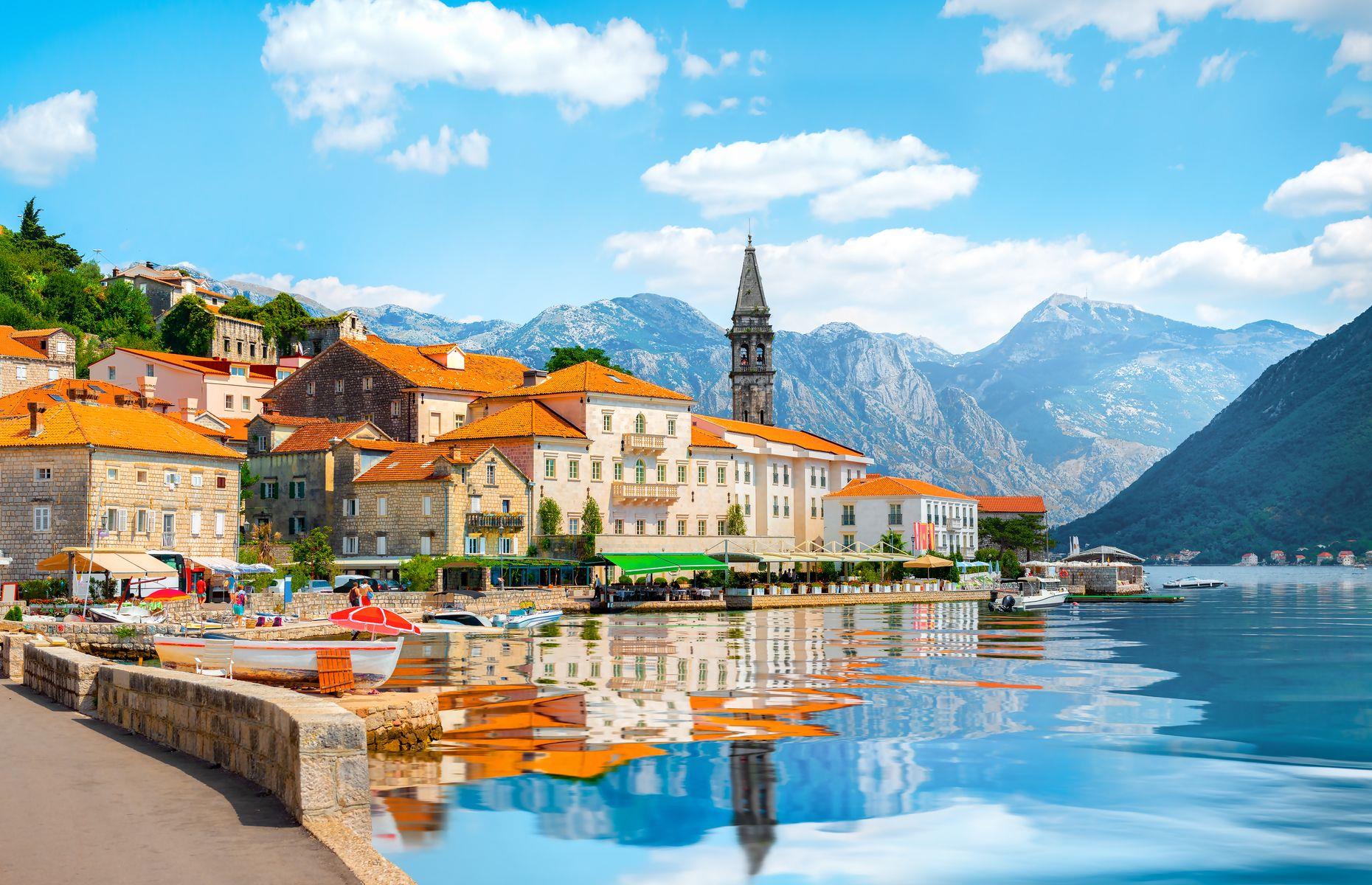 <p>Perast is a tranquil town in Montenegro’s <a href="https://www.loveexploring.com/news/93422/weekend-break-kotor-montenegro-europe-2020-holidays">Kotor</a> Bay. Met by mirror-like waters that perfectly reflect its terracotta-roofed houses, the town looks as pretty as a picture. Don’t be fooled by its small size – it has a whopping 16 churches, which includes the unfinished Church of St. Nicholas. The spire of the 17th-century church rises in the background of this enchanting photo.</p>