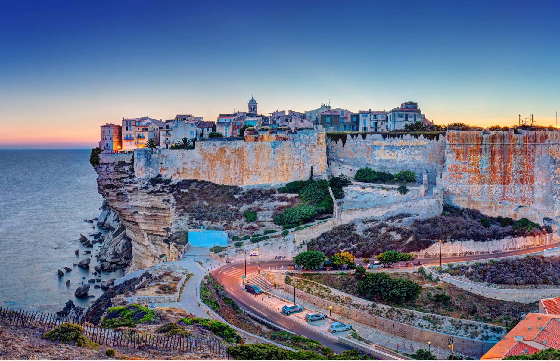 <p>With its precarious position on top of a narrow limestone plateau, Bonifacio looks especially spellbinding by nightfall, when its buildings are illuminated by polychromatic lights. Located on Corsica’s southernmost tip, the settlement was established in about AD 828 by Count Boniface of Tuscany, and it became an important strategic location for defending Corsica against pirates. </p>  <p><strong><a href="https://www.loveexploring.com/gallerylist/100075/on-the-edge-the-worlds-most-perilous-places">Discover the world's most precarious places</a></strong></p>