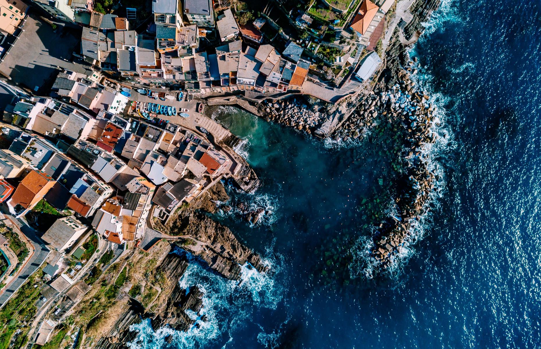 <p>Known for its vertiginous cliffs, rocky coves and dainty, colorful houses, northern Italy’s Cinque Terre is made up of five villages: Riomaggiore, Manarola, Corniglia, Vernazza and Monterosso. Pictured here is Riomaggiore, the region’s easternmost village, its pastel-toned rooftops and colorful wooden fishing boats set against deep blue waters.</p>  <p><strong><a href="https://www.loveexploring.com/gallerylist/104543/the-worlds-most-beautiful-coastal-towns-and-villages">Discover the world's most beautiful coastal towns and villages here</a></strong></p>