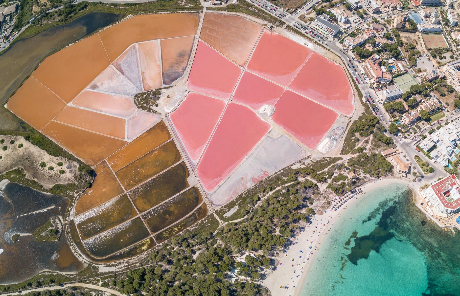 Resembling a magnificent paint palette of corals, pinks, and browns, the salt lakes of Colonia Sant Jordi are spectacular from the skies. Situated on the south coast of Mallorca, more than 10,000 tons of speciality “Flor de Sal” sea salt are mined from here each year.
