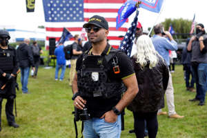 a group of people standing on top of a grass covered field: Proud Boys leader Henry “Enrique” Tarrio was arrested Jan. 4 and charged with destruction of property in connection with the burning of a Black Lives Matter banner outside a D.C. church in December. (Joshua Lott/The Washington Post)