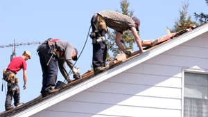 a group of people standing on top of a ramp: Men repairing roof