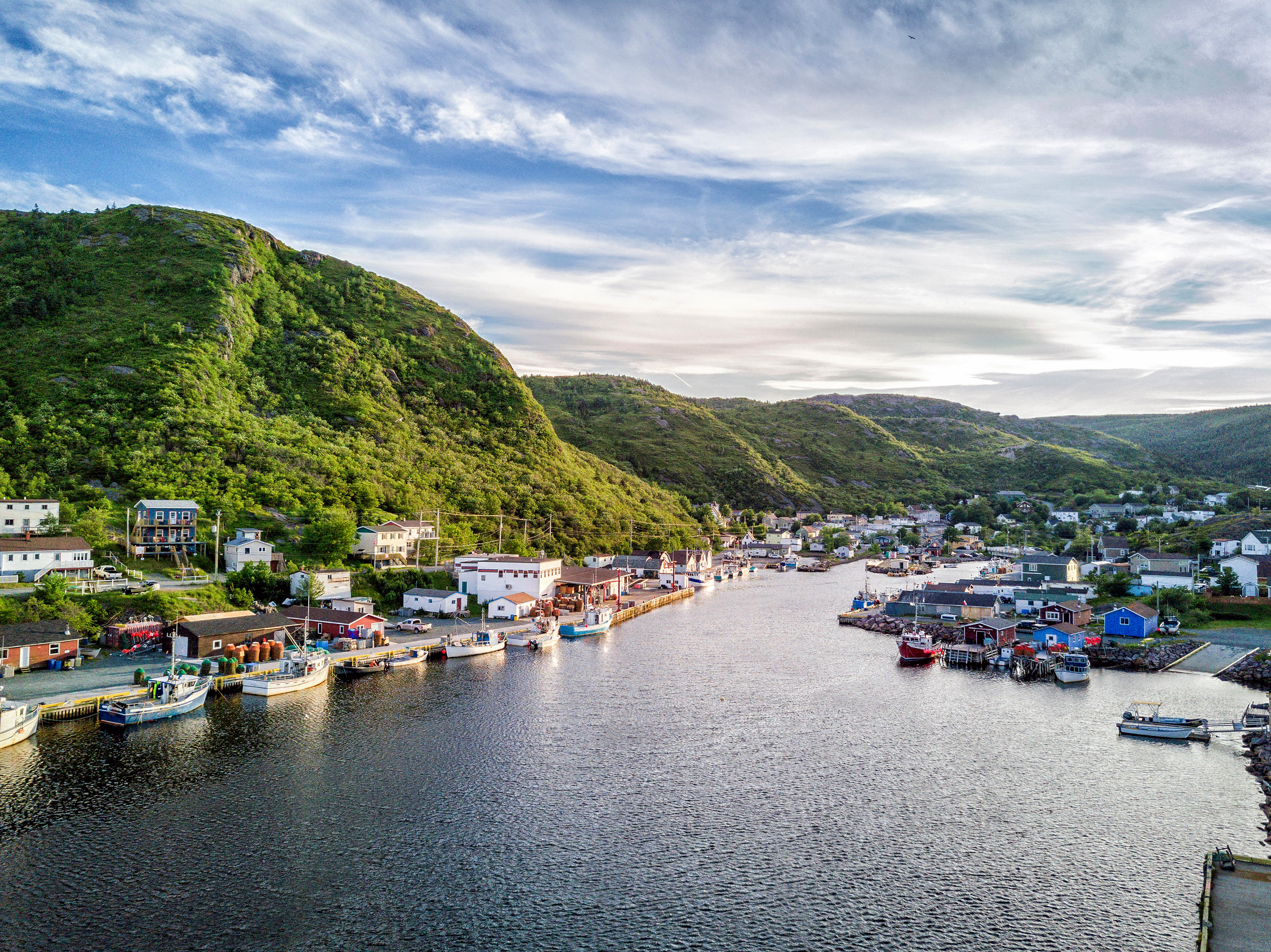 Slide 6 of 41: Charming Petty Harbour with green hills and colorful wooden architecture, Newfoundland, Canada