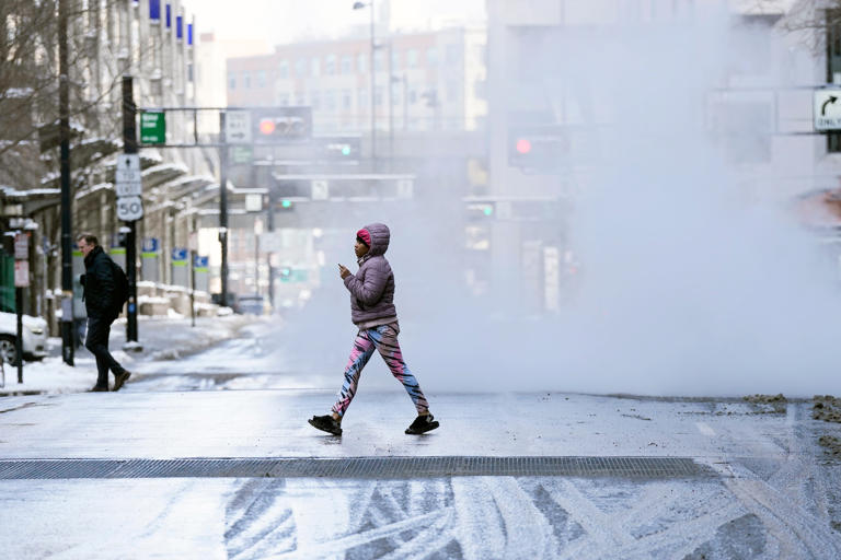 A woman crosses Fifth Street near Fountain Square Friday, January 19, 2024, after snow had been removed from many of the streets in downtown Cincinnati.